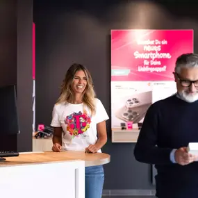 Mitarbeiterin im Mobilfunk-Shop berät Kunden zu Smartphones und Tarifen