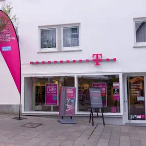 Telekom Shop mit Werbeschildern und Angeboten für Internet, TV und Mobilfunk am Gehweg.
