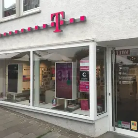Telekom Shop mit Glasfront, Werbeplakat und Telekom Logo in einer deutschen Innenstadt.